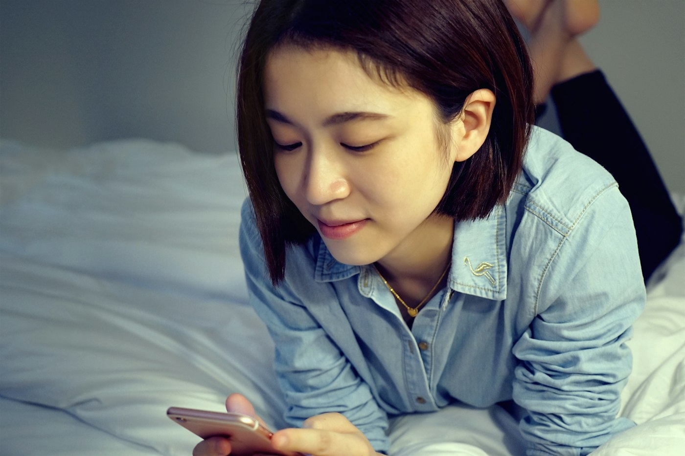 ベッドでスマートフォンを見る女性
